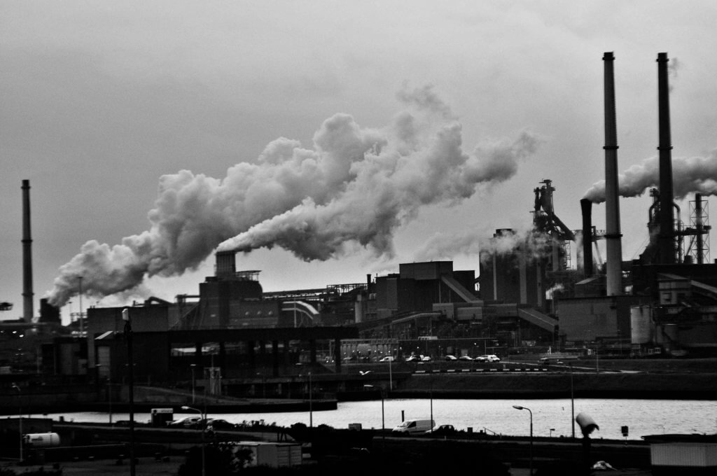 Gases sendo expelidos por várias chaminés de uma fábrica