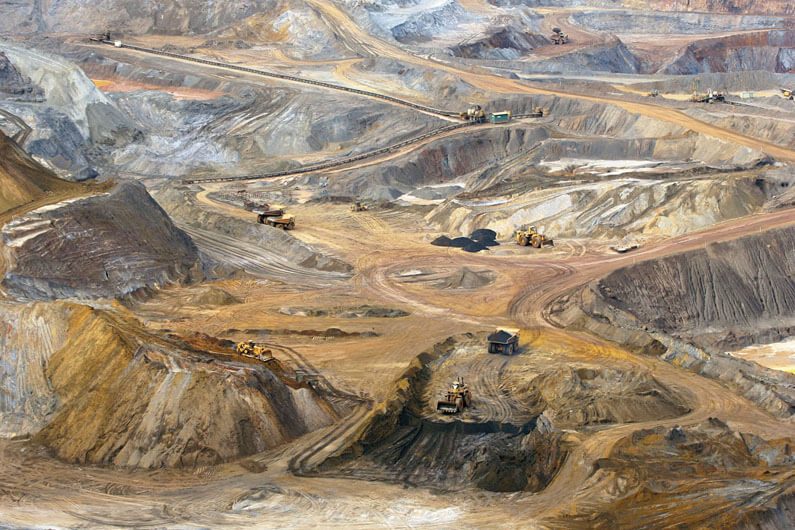 Imagem de escavadeiras e caçambas numa mina de minério de ferro ilustra o post que aborda sobre o que fazer com os rejeitos gerados pela exploração mineral.