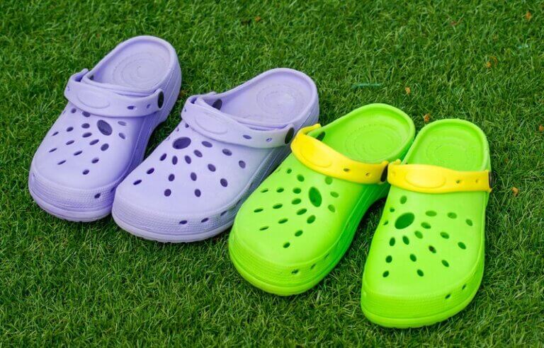 Imagem de dois pares de sapatos Crocs sobre um terreno gramado ilustra o post que aborda como a Crocs tem reduzido a pegada de carbono de seus sapatos.