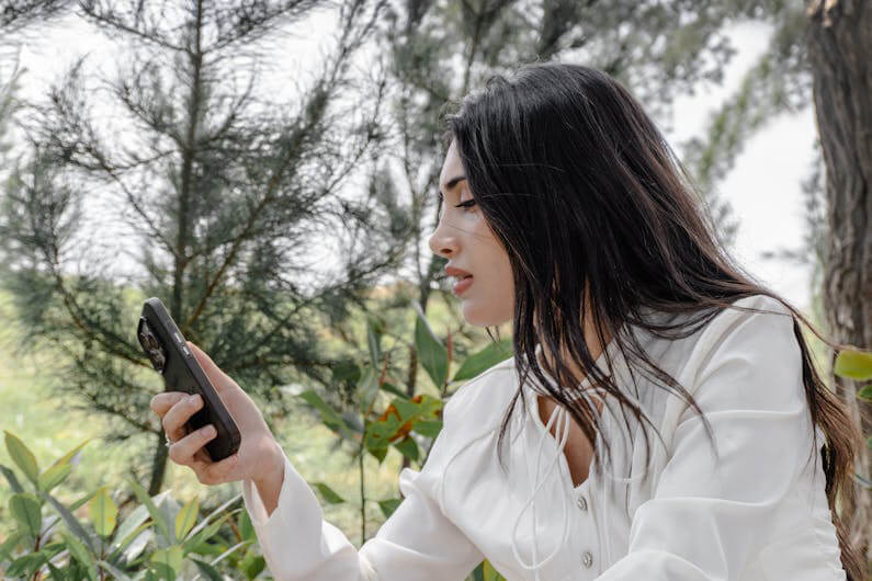 Imagem de uma mulher jovem olhando para um celular em sua mão ilustra o post cujo título diz que as mídias sociais causam ansiedade em jovens da Flórida, diz estudo