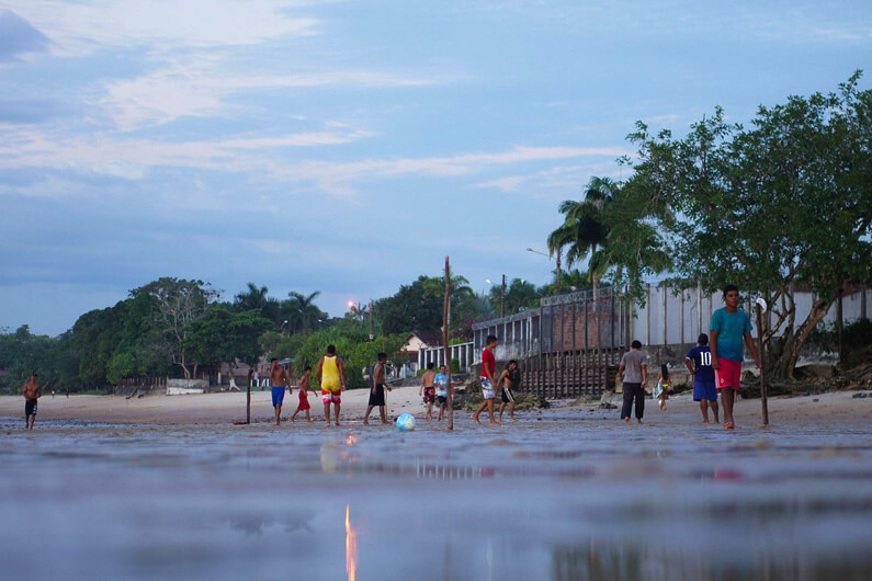 Imagem mostrando meninos jogando futebol na Praia de São Francisco, em Belém do Pará, ilustra a matéria cujo título pergunta: por que a COP30 foi considerada um fracasso?
