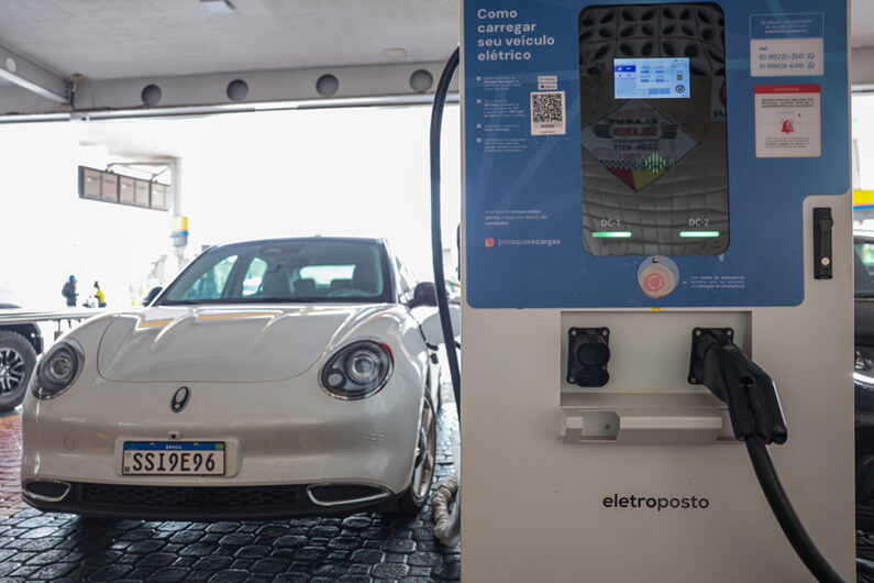 Imagem de um veículo elétrico sendo abastecido em um ponto de carregamento ilustra post cujo título diz que o reciclo de baterias patina no Brasil apesar do boom dos elétricos.