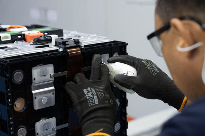 Imagem de um homem trabalhando em uma bateria para veículos elétricos ilustra post cujo título diz que o reciclo de baterias patina no Brasil apesar do boom dos elétricos.