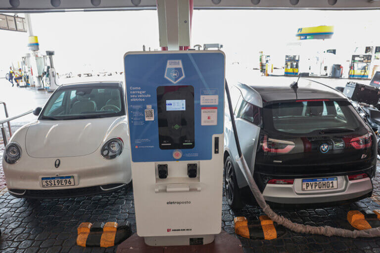 Imagem de dois veículos elétricos sendo carregados em um ponto de abastecimento ilustra o artigo que diz que o Brasil já possui 21 mil pontos de recarga para veículos elétricos.