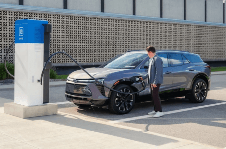 Imagem de um veículo elétrico sendo abastecido por um homem ilustra o post que diz que a venda de EVs usados nos EUA dispara e a de novos despenca.