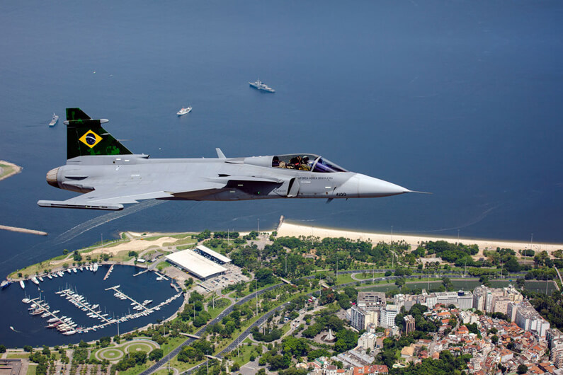Imagem do avião Grippen sobre a cidade do Rio de Janeiro ilustra o post cujo título diz que o Brasil é o primeiro país latino-americano a produzir jatos supersônicos.