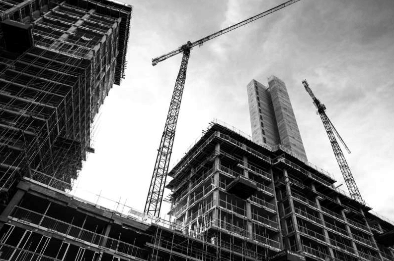 Imagem de gruas por trás de prédios em construção ilustra o post que diz que as casas sustentáveis podem tornar moradias mais acessíveis.