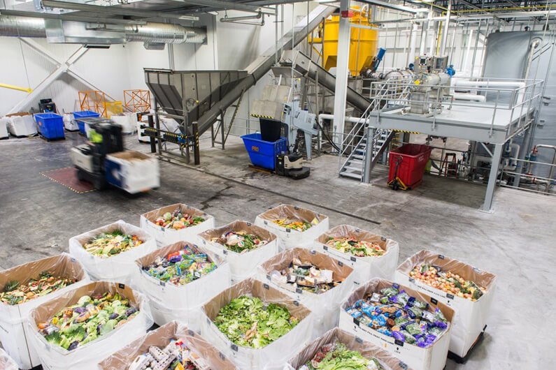 Imagem da área interna de uma empresa mostra várias caixas cheias de resíduos de alimentos ilustra o post que aborda por que o processamento de resíduos de alimentos está crescendo.
