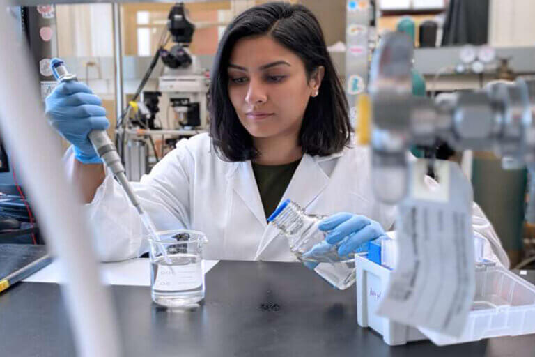 Foto da primeira autora do estudo científico manipulando um pipeta dentro de um laboratório ilustra o post cujo título diz que a solidão reprograma o cérebro e aumenta o consumo de álcool.