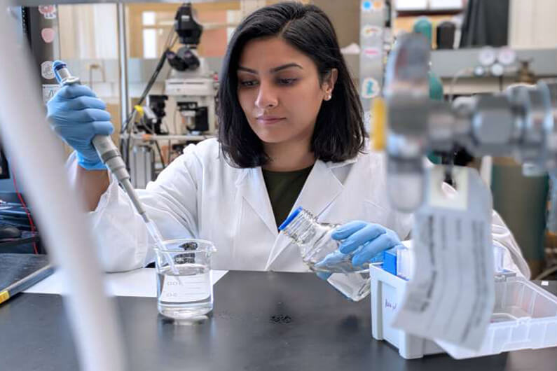 Foto da primeira autora do estudo científico manipulando um pipeta dentro de um laboratório ilustra o post cujo título diz que a solidão reprograma o cérebro e aumenta o consumo de álcool.