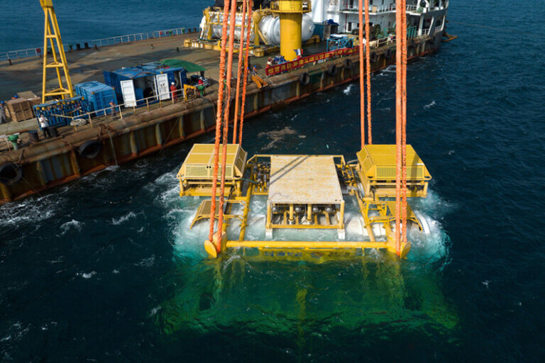 Imagem de uma plataforma amarela que tem uma parte sobre o mar e outra submersa ilustra o post cujo título diz que os data centers submersos no mar da China geram dúvida ambiental.